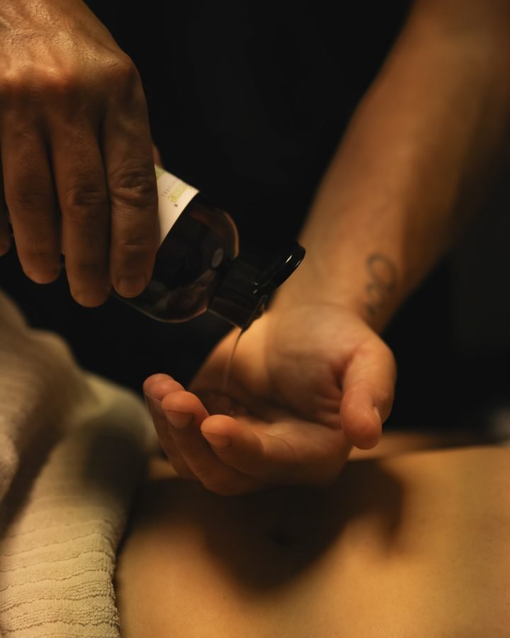 Aceite de masaje vertiéndose sobre la mano antes de empezar la sesión